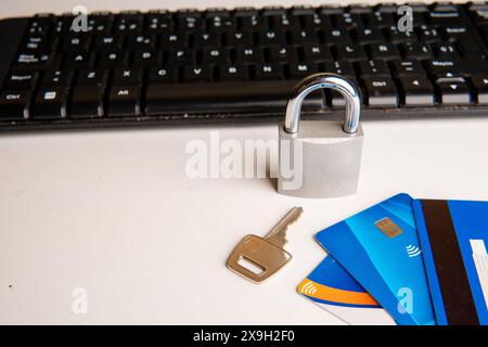 Concept de contrôle des dépenses, un cadenas fermé et une clé à côté des cartes de crédit, en arrière-plan un clavier d'ordinateur, sur un fond blanc. Banque D'Images