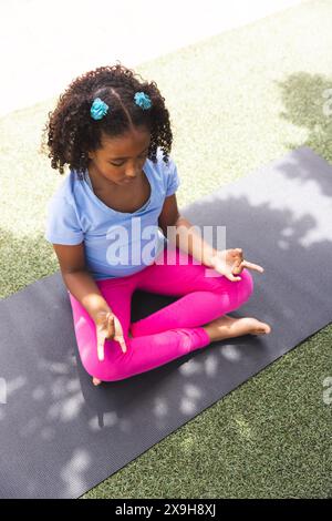 Une fille biraciale pratique le yoga à l'extérieur à l'école, avec un espace de copie Banque D'Images