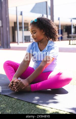 Une fille biraciale pratique le yoga à l'extérieur à l'école Banque D'Images