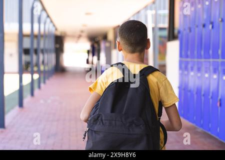 Garçon biracial marche dans un couloir d'école Banque D'Images