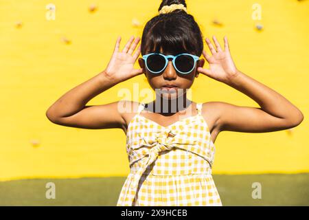 Fille biraciale pose dans des lunettes de soleil ludiques Banque D'Images