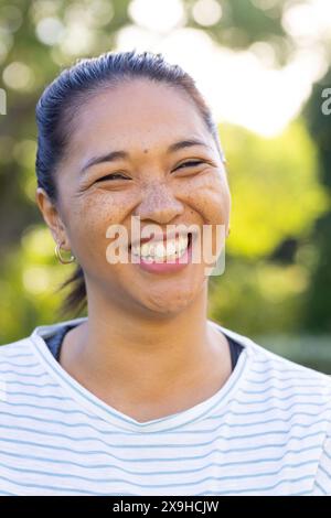 À l'extérieur, femme biraciale dans la trentaine souriant brillamment à la lumière du soleil Banque D'Images