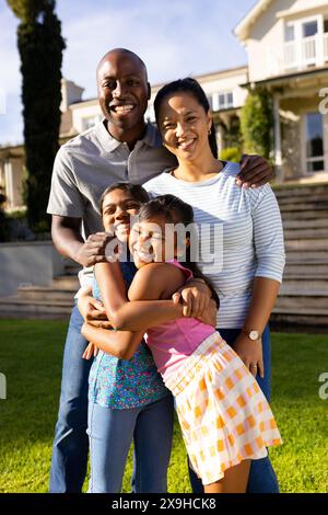 À l'extérieur, famille diversifiée de quatre personnes est souriant et serrant, devant la maison Banque D'Images