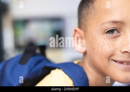 Garçon biracial dans le sourire jaune excité en classe, prêt pour l'école. Banque D'Images