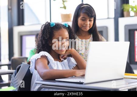 À l'école, deux jeunes étudiantes biraciales regardant un écran d'ordinateur portable dans la salle de classe Banque D'Images