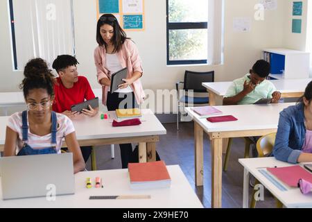 Jeune enseignante biraciale enseigne dans une salle de classe de lycée, avec espace de copie Banque D'Images