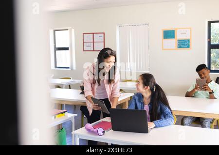 Professeur biracial éduque les adolescents, l'un distrait par téléphone. Banque D'Images