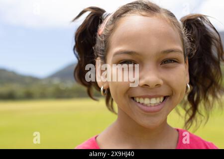 Fille biraciale avec un sourire joyeux se tient à l'extérieur Banque D'Images