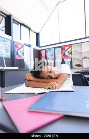 Garçon biracial endormi dans la salle de classe à l'école Banque D'Images