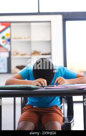 Garçon biracial concentré sur le dessin dans la salle de classe à l'école Banque D'Images