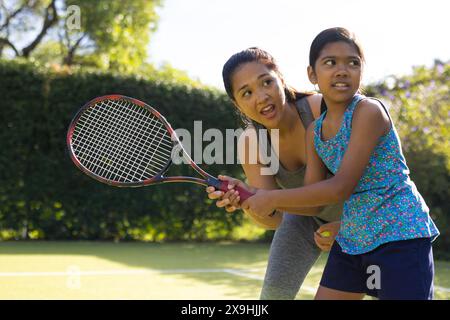 En plein air, mère biraciale et fille jouant au tennis le jour ensoleillé Banque D'Images