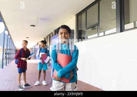 Trois garçons biraciaux sont debout dans un couloir scolaire Banque D'Images