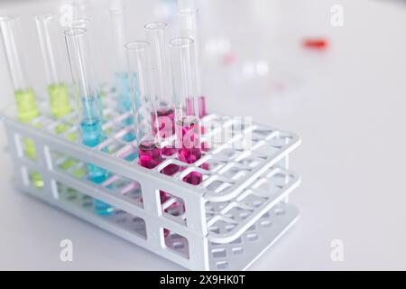 Tubes à essai remplis de liquides colorés dans un rack de laboratoire, avec espace de copie. Les teintes vibrantes suggèrent diverses réactions chimiques ou tests en cours de réalisation i Banque D'Images