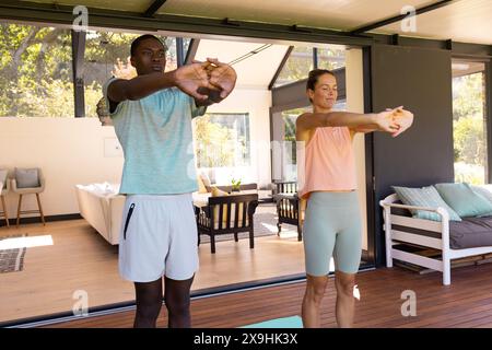 Un jeune couple diversifié s'étirant à l'extérieur, tous deux en tenue sportive Banque D'Images