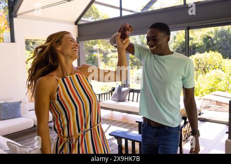 Un jeune couple diversifié dansant joyeusement à la maison Banque D'Images