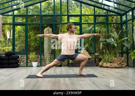 Le studio de maison de verre capture la pratique d'instructeur de yoga masculin caucasien Banque D'Images