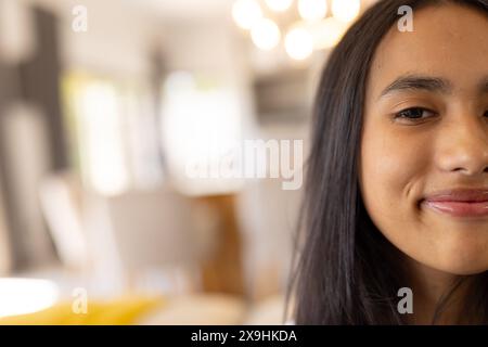 Une jeune fille biraciale souriant à la maison avec de longs cheveux bruns, espace de copie Banque D'Images