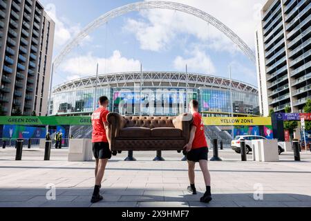 USAGE ÉDITORIAL EXCLUSIF Bradley Lemaire (à gauche) et Callum Barton (à droite) livrent un canapé appartenant aux vainqueurs de la compétition, Sarah carter et Mark Slaughter, au stade de Wembley à Londres, avant la finale de l'UEFA Champions League ce soir, dans le cadre de la compétition « No Walkers, No Game » des Walkers. Date d'émission : samedi 1er juin 2024. Banque D'Images