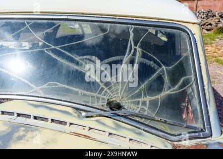 Vue en coupe avant rapprochée d'une voiture d'époque rouillée et endommagée dont le pare-brise est gravement fissuré. Concept de restauration de voiture classique. Banque D'Images