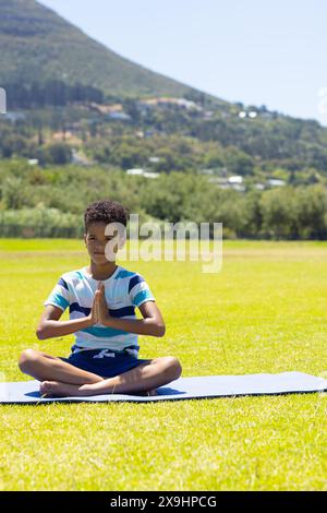 Biracial Boy pratique le yoga en plein air par une journée ensoleillée, avec un espace de copie Banque D'Images