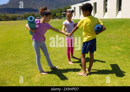 Les enfants biraciaux se préparent pour une séance de yoga en plein air par une journée ensoleillée Banque D'Images
