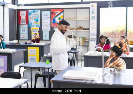 Professeur asiatique avec flacon par divers étudiants dans l'expérience de science scolaire Banque D'Images