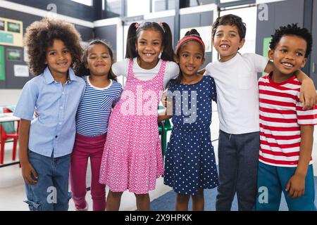 À l'école, six jeunes élèves sont debout ensemble en classe, souriants Banque D'Images