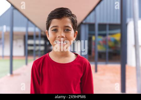 À l'école, jeune garçon biracial avec un sourire brillant debout dehors Banque D'Images