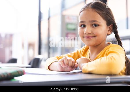 À l'école, une jeune fille biraciale avec une tresse apprend en classe Banque D'Images