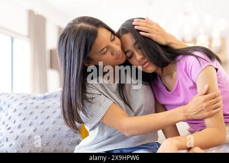 Deux jeunes sœurs biraciales embrassant chaleureusement à la maison Banque D'Images