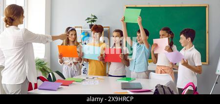 Élèves de l'école primaire montrant des feuilles de papier vierges à l'enseignant en classe Banque D'Images