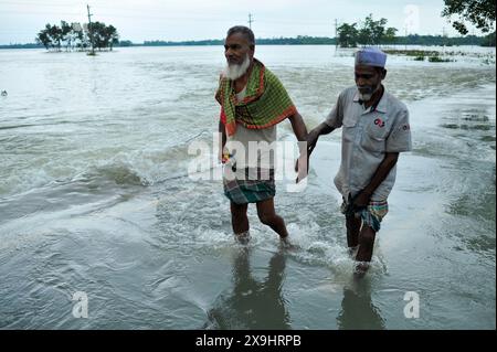 Sylhet, Bangladesh. 30 mai 2024. Les résidents âgés ont du mal à patauger sur la route principale inondée dans le quartier Lafnaut de Gowainghat upazila de Sylhet. Les pluies continues du cyclone Remal ont provoqué l'écoulement de l'eau des collines environnantes, submergeant la route depuis hier. Il est à noter que de nombreuses personnes ont quitté leur domicile et se sont rendues dans des refuges sûrs. Les zones basses et horifères de trois syndicats de l'upazila de Jaintapur à Sylhet sont inondées en raison de crues soudaines provoquées par de fortes pluies et de l'eau des pentes des collines. Environ 300 mille personnes dans quatre upazilas ont été piégées dans l'eau due Banque D'Images