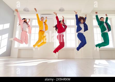 Groupe d'amis énergiques, habillés de costumes de couleur vive, sauter simultanément. Banque D'Images