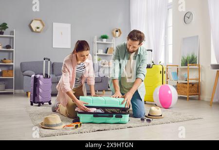 Couple d'aventure à venir joyeusement emballer des sacs en sélectionnant des articles pour emballer leurs sacs pour Journey Ahead. Soigneusement choisi détient de nouvelles expériences chères Banque D'Images