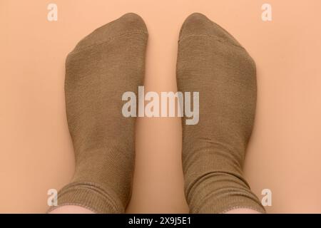 Jambes féminines en chaussettes brunes sur fond beige Banque D'Images