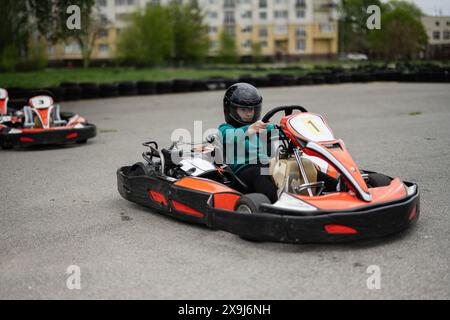 Enfant dans un casque noir conduisant un Go-kart pendant une course intense. Vivez les sensations fortes des courses de karting. Banque D'Images