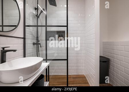 Salle de bains moderne avec douche vitrée et murs carrelés blancs Banque D'Images