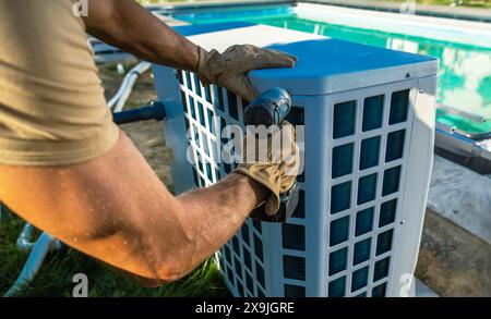 Technicien CVC installant un chauffe-piscine près de la piscine Banque D'Images