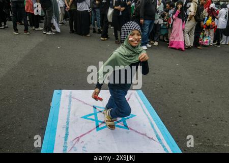 Des piétons marchent sur un drapeau israélien lors d’une manifestation pro-palestinienne « tous les yeux sur Rafah » à Bogor, Java occidental, Indonésie, le 1er juin 2024. Banque D'Images