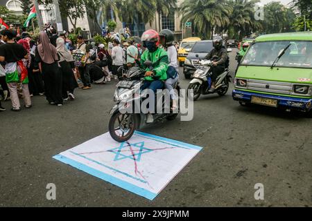 Un motocycliste survole un drapeau israélien lors d’une manifestation pro-palestinienne « tous les yeux sur Rafah » à Bogor, Java occidental, Indonésie, le 1er juin 2024. Banque D'Images