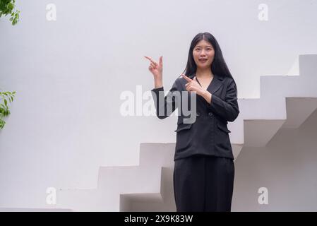 Portrait d'une femme professionnelle en tenue d'affaires exsudant la confiance sur les étapes architecturales modernes, y compris la verdure Banque D'Images