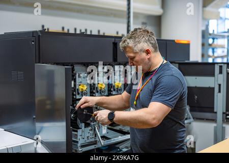 Ingénieur de maintenance dans une machine de fixation de maison d'impression Banque D'Images