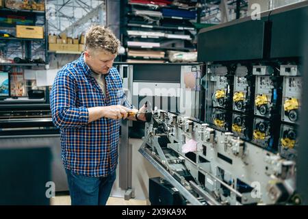 Ingénieur de maintenance dans une machine de fixation de maison d'impression Banque D'Images