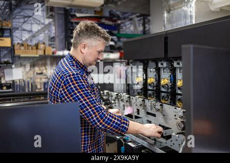 Ingénieur de maintenance dans une machine de fixation de maison d'impression Banque D'Images