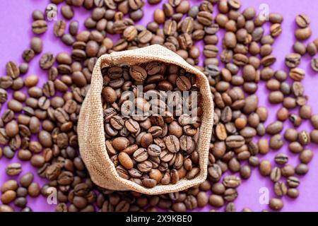 grains de café sur le fond violet avec une place pour l'inscription, grains dans un sac en toile de jute Banque D'Images