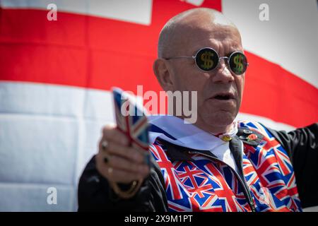 Londres, Royaume-Uni. 01 juin 2024. Un homme portant un drapeau Saint Georges rejoint la marche à travers la ville devant Tommy RobinsonÕs, le nouveau documentaire LAWFARE. La présélection publique met en évidence un système de police à deux vitesses qui, selon Tommy, est en place à l’échelle nationale. Crédit : Andy Barton/Alamy Live News Banque D'Images