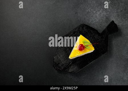 Cheesecake au citron garni de cerises, placé sur un fond noir élégant. Un régal visuel appétissant parfait pour les amateurs de desserts et de plats culinaires Banque D'Images