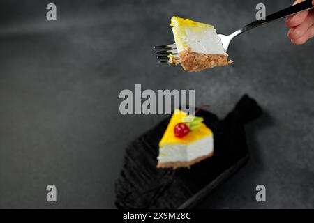 Cheesecake au citron garni de cerises, placé sur un fond noir élégant. Un régal visuel appétissant parfait pour les amateurs de desserts et de plats culinaires Banque D'Images