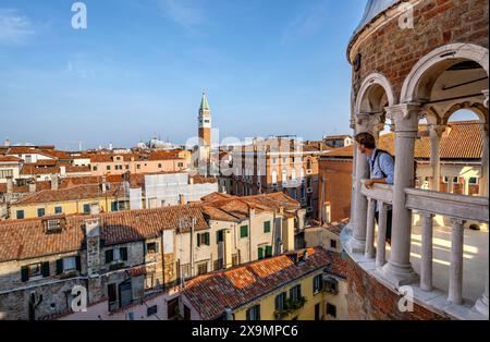 Jeune homme regardant Venise avec campanile, tour du Palazzo Contarini del Bovolo, palais avec escalier en colimaçon, Venise, Vénétie, Italie Banque D'Images