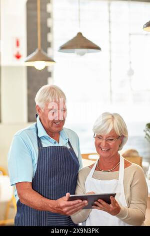 Couple senior, tablette et propriétaire d'entreprise avec planification, travail et café avec gestionnaire. Numérique, entrepreneur et personnes âgées avec site web Banque D'Images